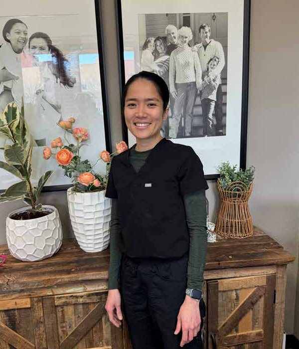 Dr. Thuy Truong smiling beside fresh flowers in the Vacaville Dental Care office