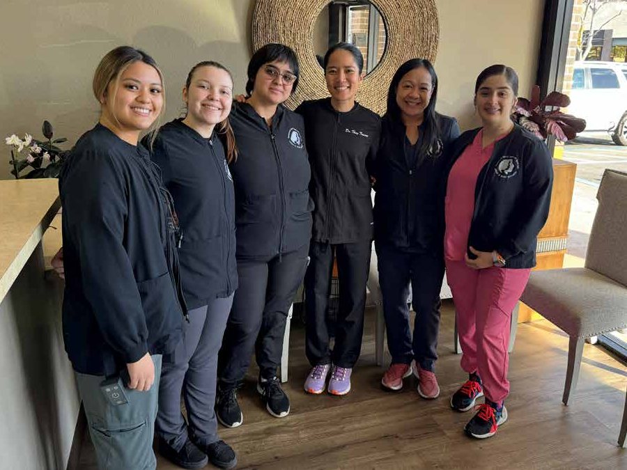 Dr. Thuy Truong and five members of the Vacaville Dental Care team standing together in the office